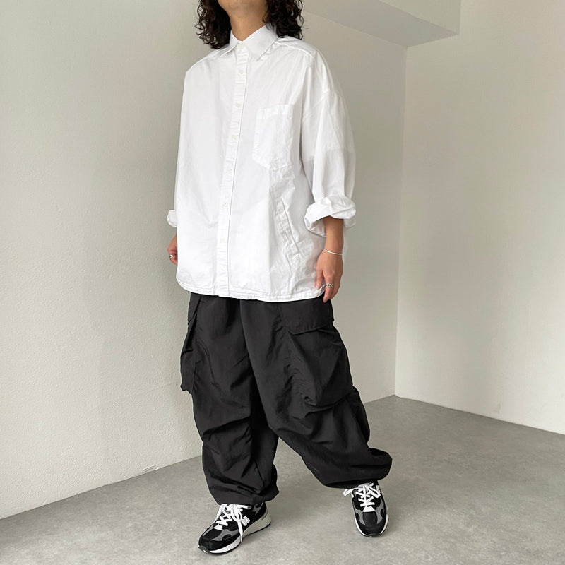 White oversized Oxford shirt with black loose cargo trousers and black-and-white sneakers